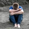 思春期の男の子がしゃがみこんで一人で悩んでいる