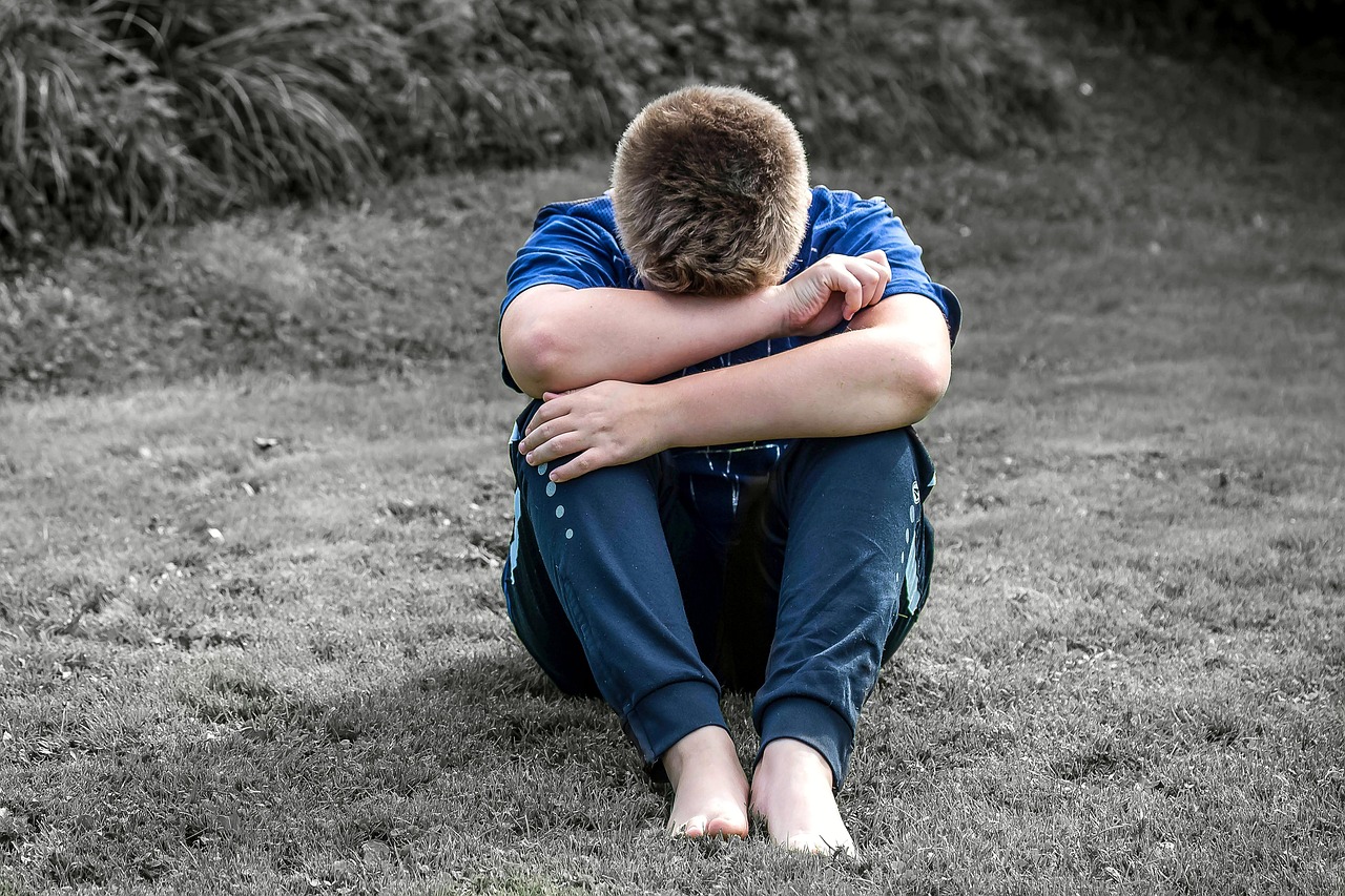 思春期の男の子がしゃがみこんで一人で悩んでいる