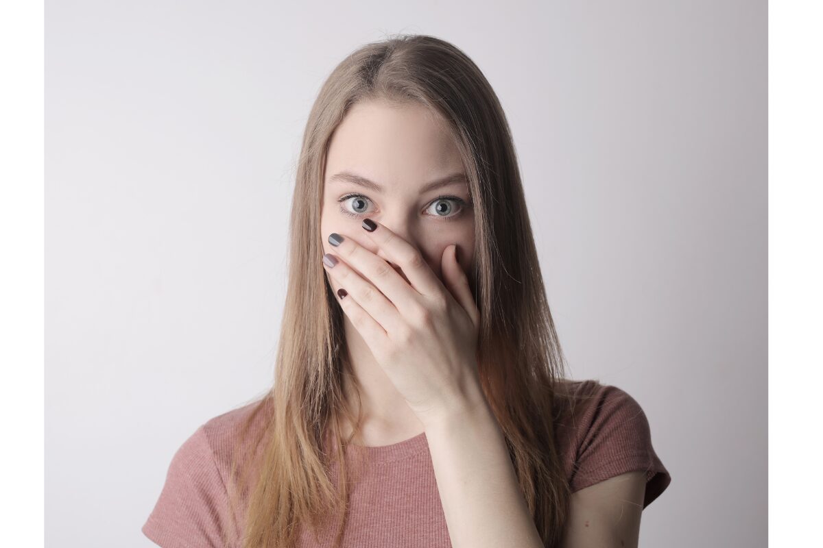 髪の長い女性が、左手で口をふさぎビックリしている。