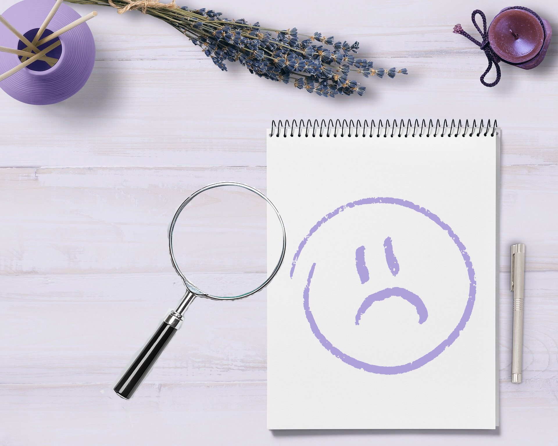 机に置かれたメモ書きとペン。メモには、悪い口コミと悪いレビューを連想させる、悲しい顔のイラスト。虫眼鏡でよく見ようとしています。