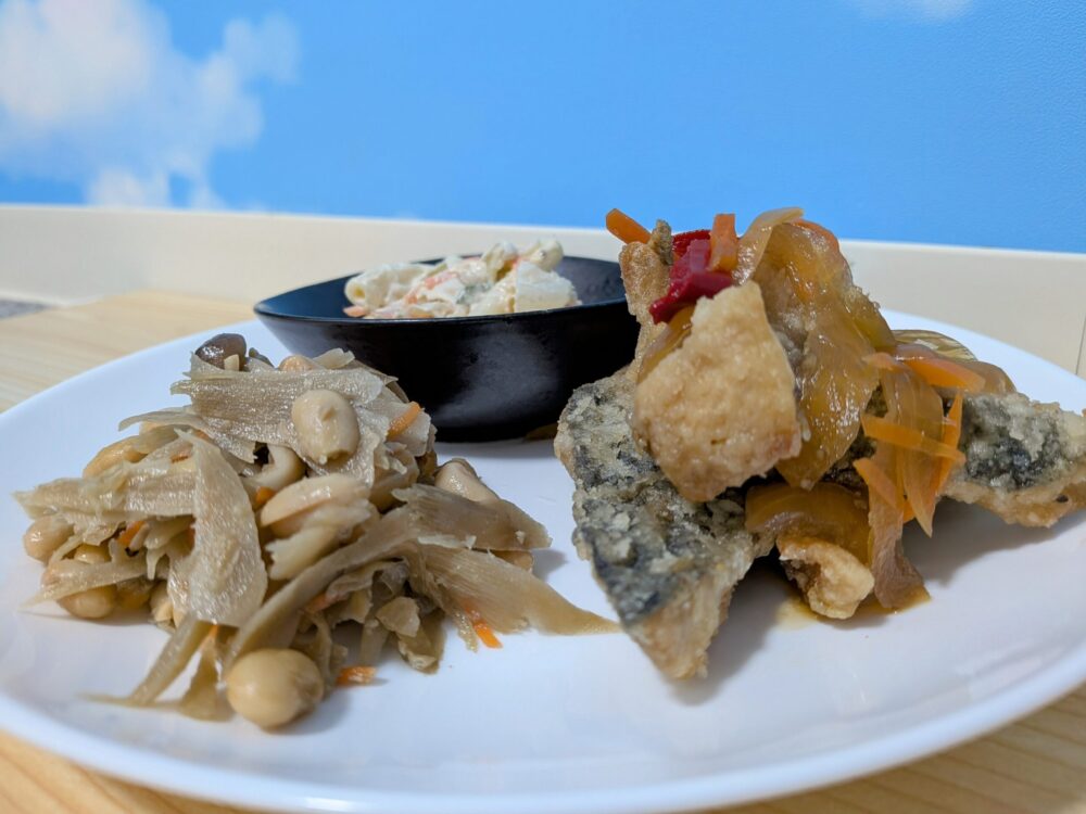 白いお皿の上に、主菜の大きなアジの唐揚げ南蛮だれかけと、副菜のマカロニサラダ、そしてゴボウと大豆としめじの炒め煮が色鮮やかにのっている。