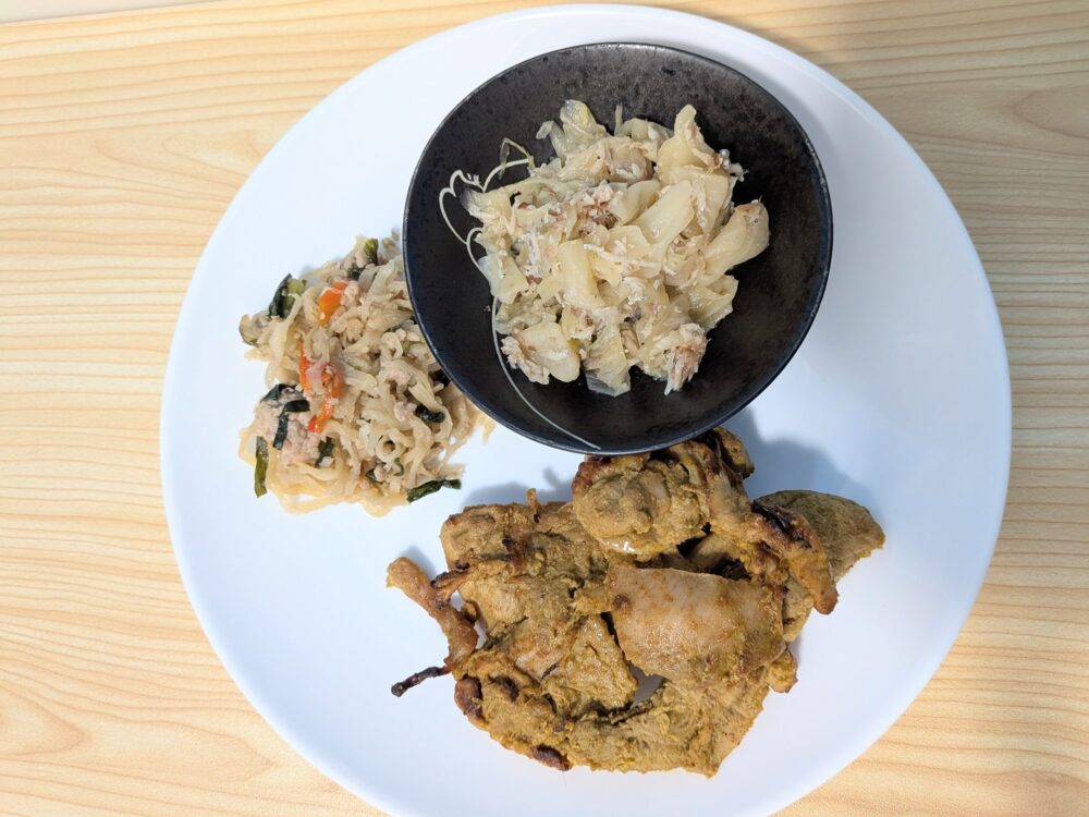 ２日目のメニューを上から撮影した写真：主菜のタンドリーチキン、副菜の切り干し大根とニラの中華炒め、キャベツのおかか和え。副菜の野菜の量がしっかりある。